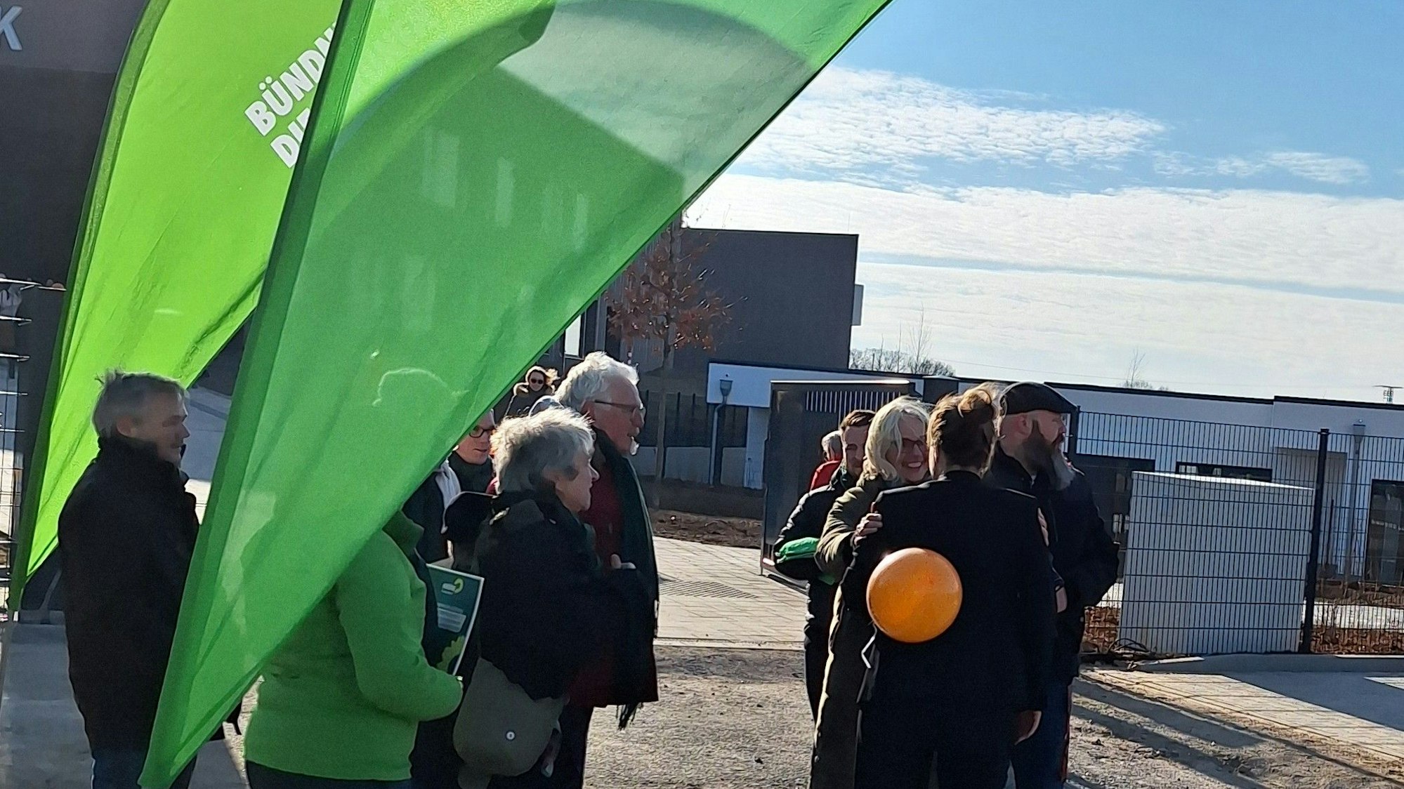 Mehrere Menschen, darunter die grüne Bürgermeisterin Claudia Wieja, stehen an einem Wahlkampfstand vor der Grundschule