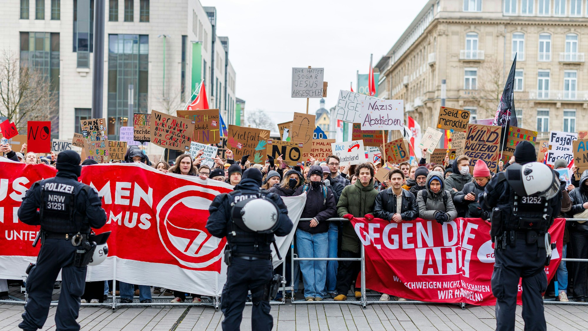 Polizeibeamte stehen in einer Kette vor der Gegendemo am Rande einer AFD-Kundgebung.