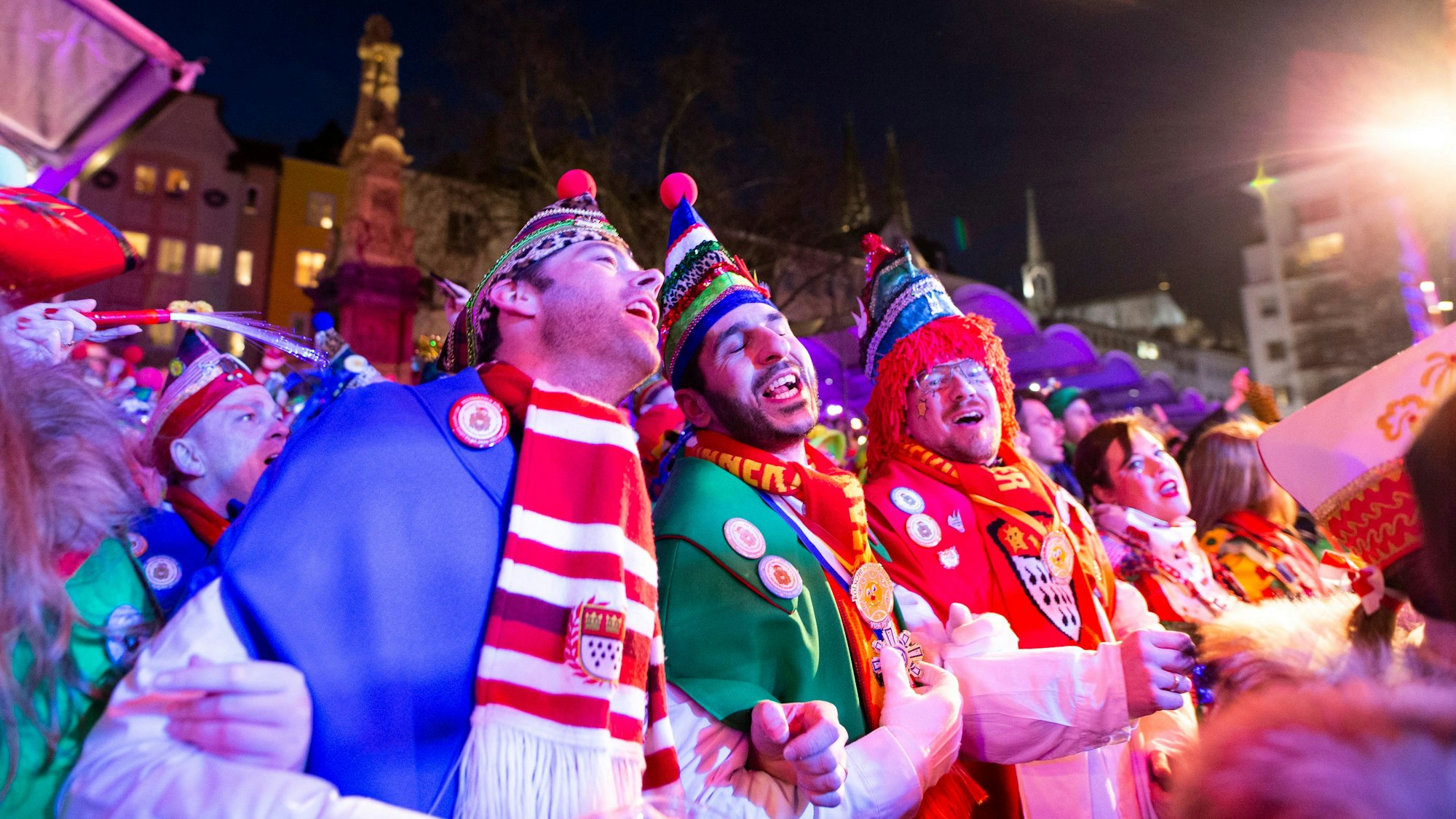 Drei verkleidete Männer schunkeln und singen auf dem Alter Markt.