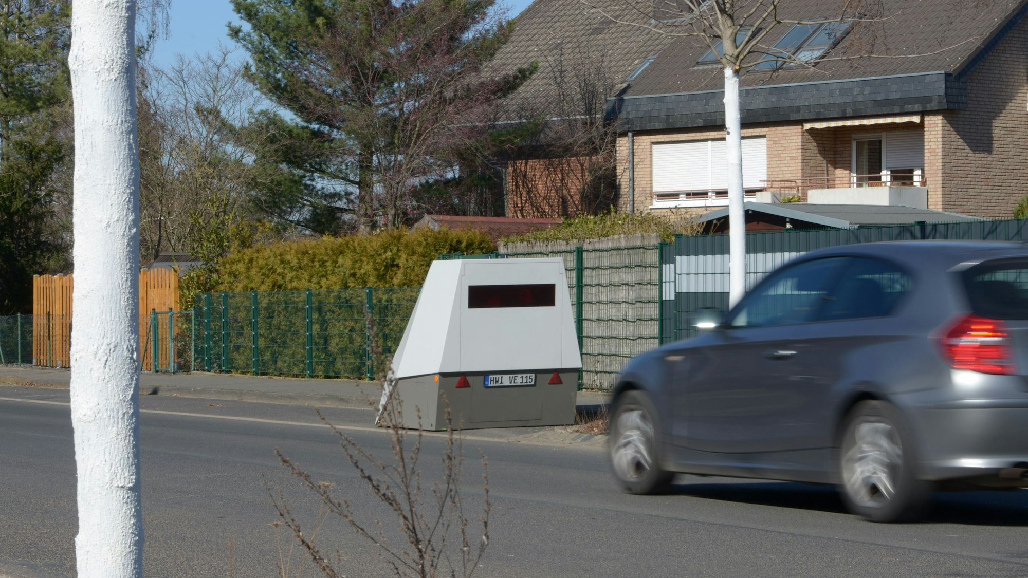 Ein Auto nähert sich einer Geschwindigkeitsmessanlage, die am Straßenrand steht.