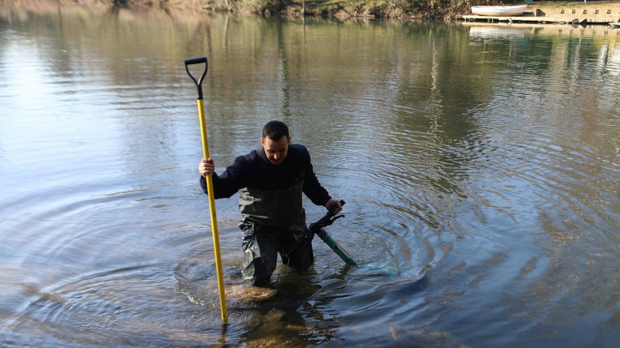 Ein Feuerwehrmann hat einen E-Scooter in der einen sowie einen Einreißhaken in der anderen Hand.