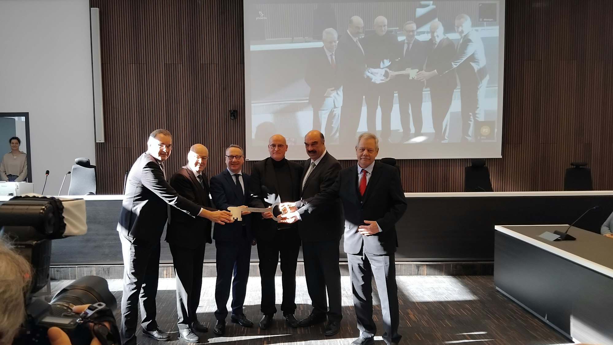 Sechs Männer halten einen symbolischen Schlüssel