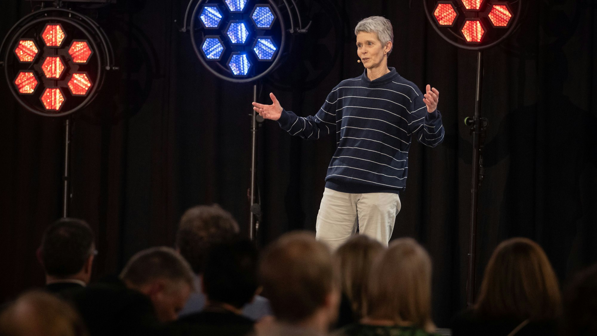 Dany Kemmler steht auf einer Bühne vor roten und blauen Scheinwerfern. Vor ihr sitzt das Publikum.