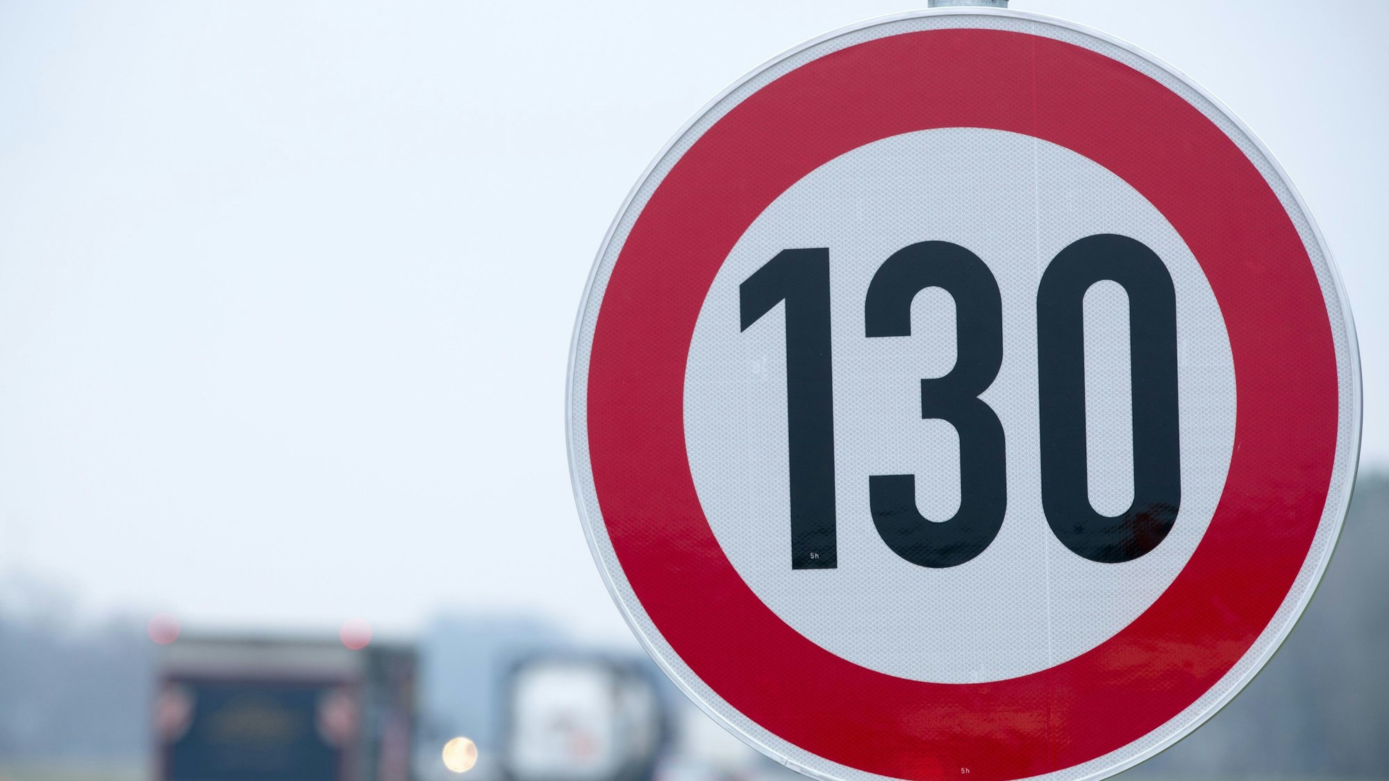 An der Autobahn steht ein Verkehrsschild mit der Geschwindigkeitsangabe von 130 km/h.