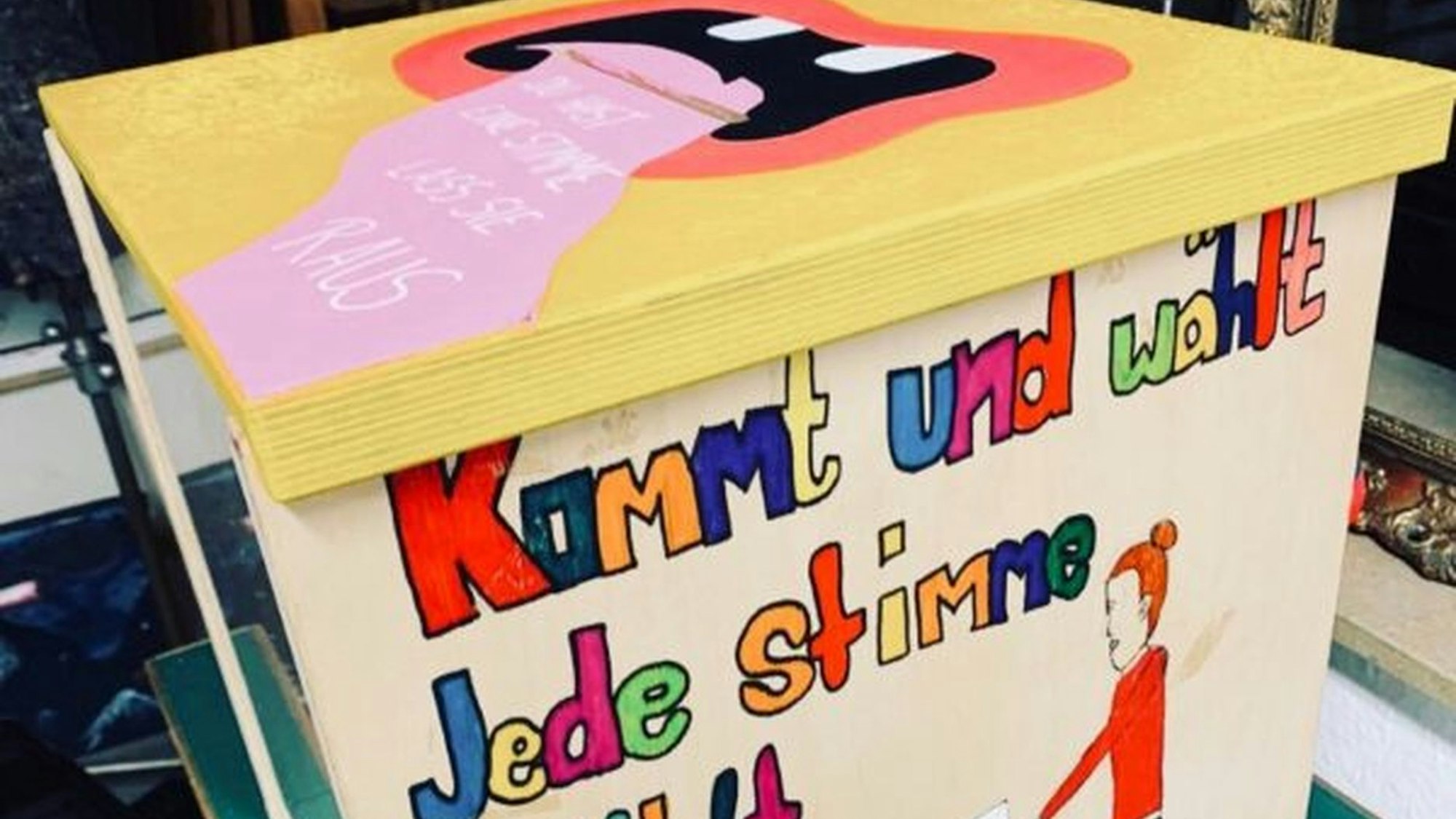 Von Jugendlichen bunt bemalte und mit einer Wahlaufforderung versehene Wahlurne für die U18-Wahlen vor der Bundestagswahl im Februar 2025.