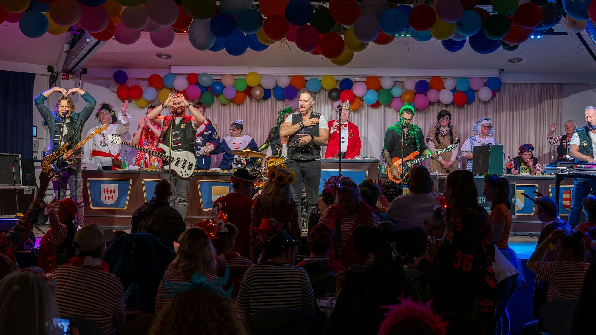 Vier Männer einer Band performen auf einer bunt dekorierten Bühne.