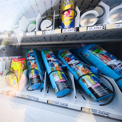 Ein Warenautomat, unter anderem mit Lachgasflaschen bestückt, steht vor einem Ladengeschäft.