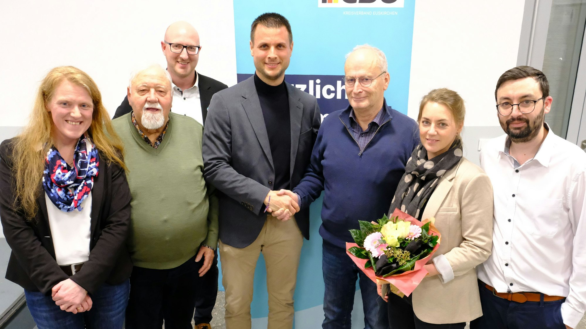 Hans-Peter Schick gratuliert Michael Fingel zur Wahl zum Bürgermeisterkandidaten. Weitere Parteivertreter haben sich mit den beiden zum Gruppenbild vor einem CDU-Banner aufgestellt.