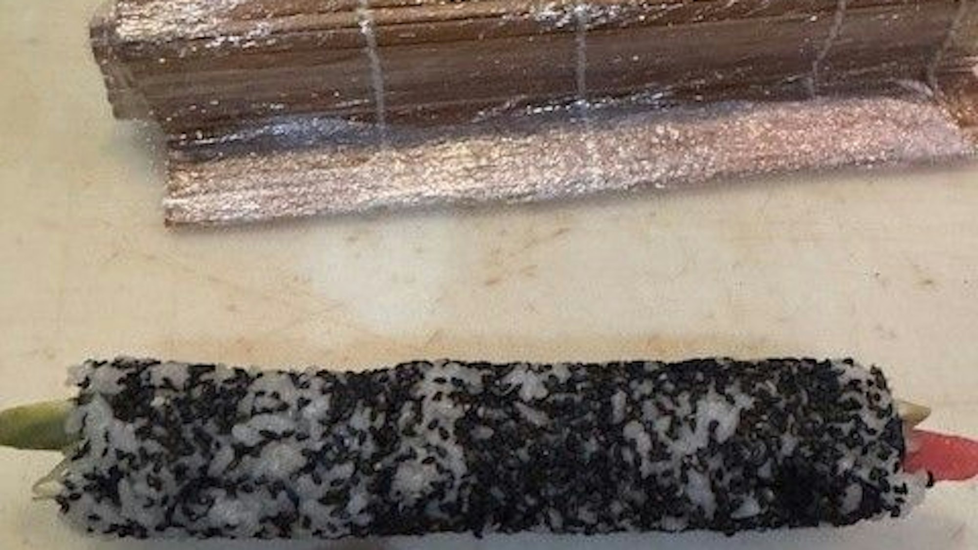 Matte aufrollen, mit dem Cellophan entfernen, Tuna Roll in Stücke schneiden.