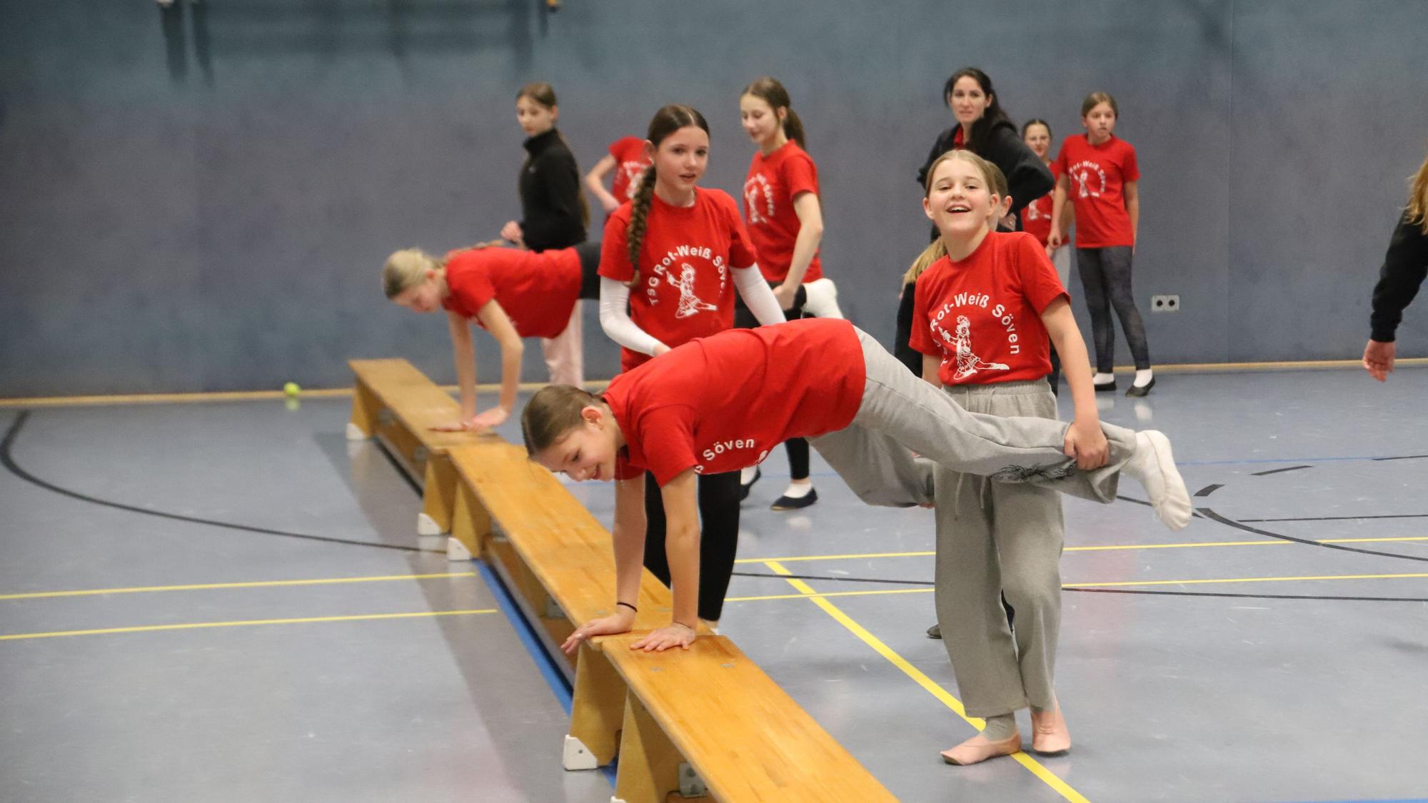Mädchen trainieren in einer Turnhalle.