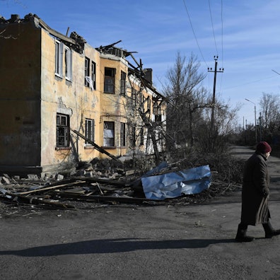 Ein Anwohner geht an einem schwer beschädigten Haus entlang.