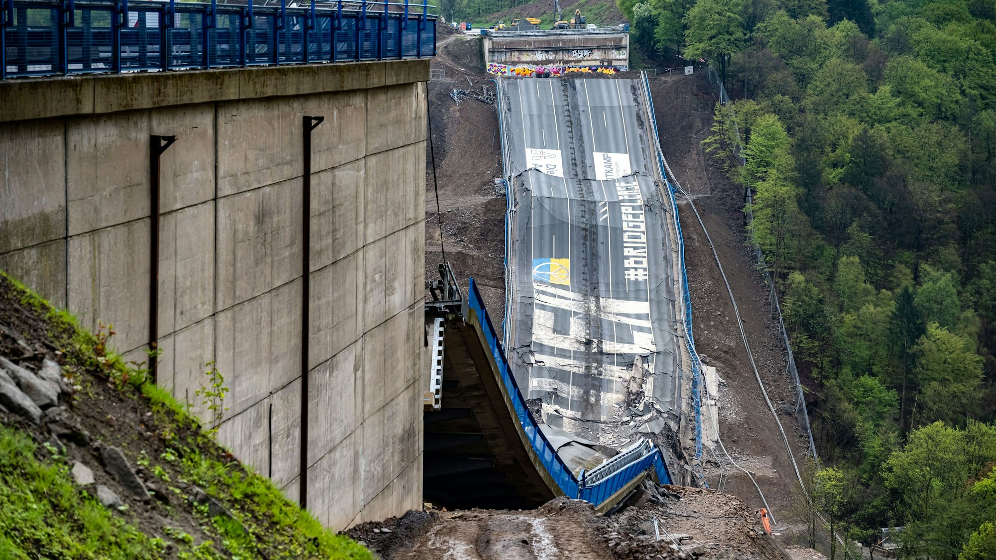 Nach der erfolgreichen Sprengung liegt die Rahmedetalbrücke auf dem Boden, Teile der Fahrbahn sind zu sehen.