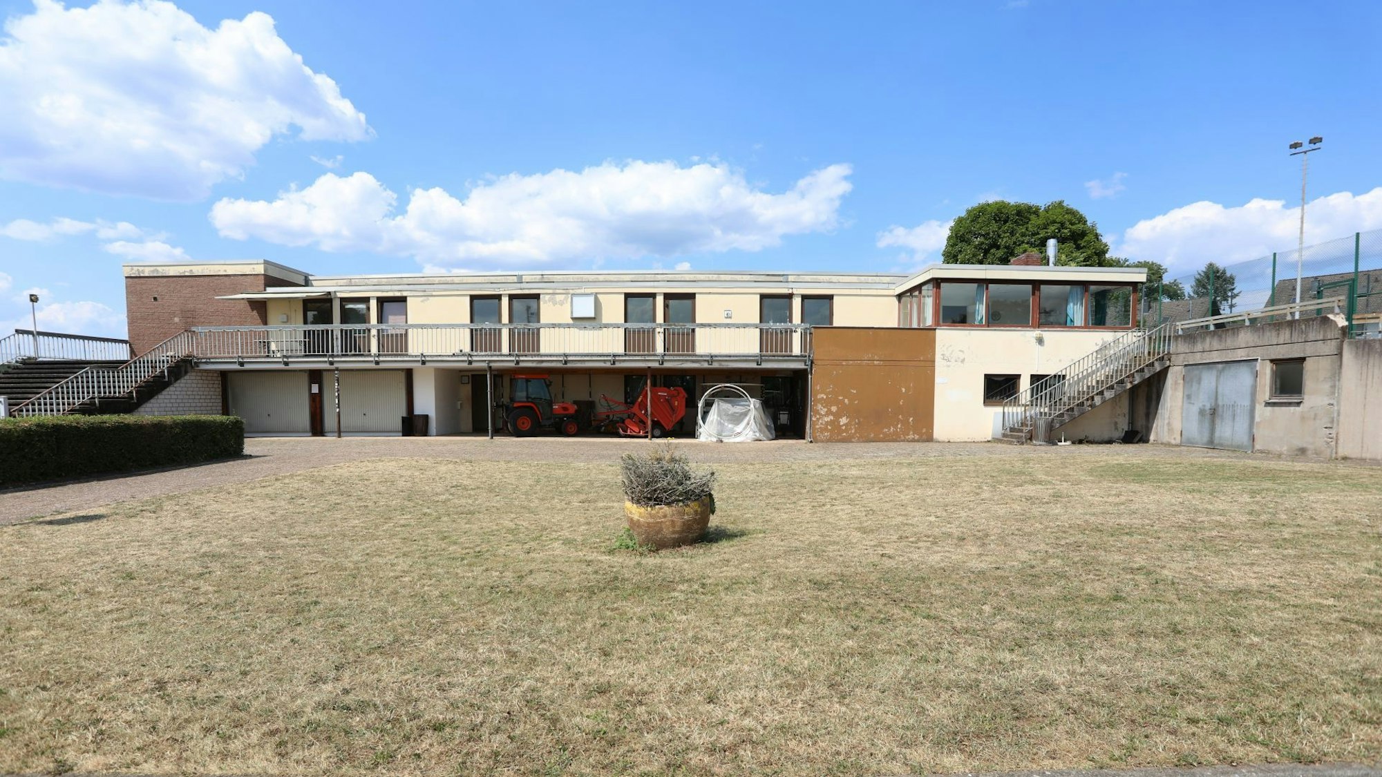 Die Rückseite einer Sporthalle mit einer großen Rasenfläche davor.