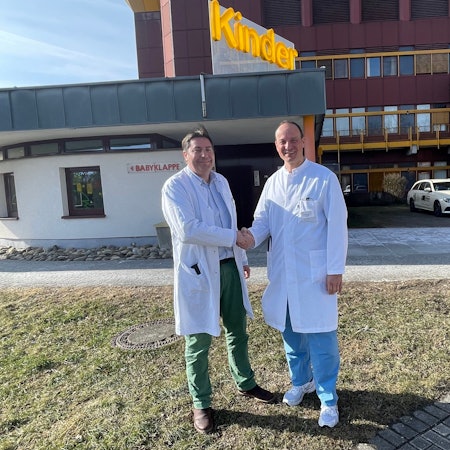 Zwei Ärzte schütteln sich vor einem Krankenhaus die Hände.