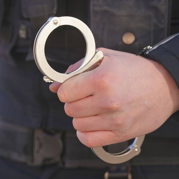 Polizist hält Handschellen in der Hand.
