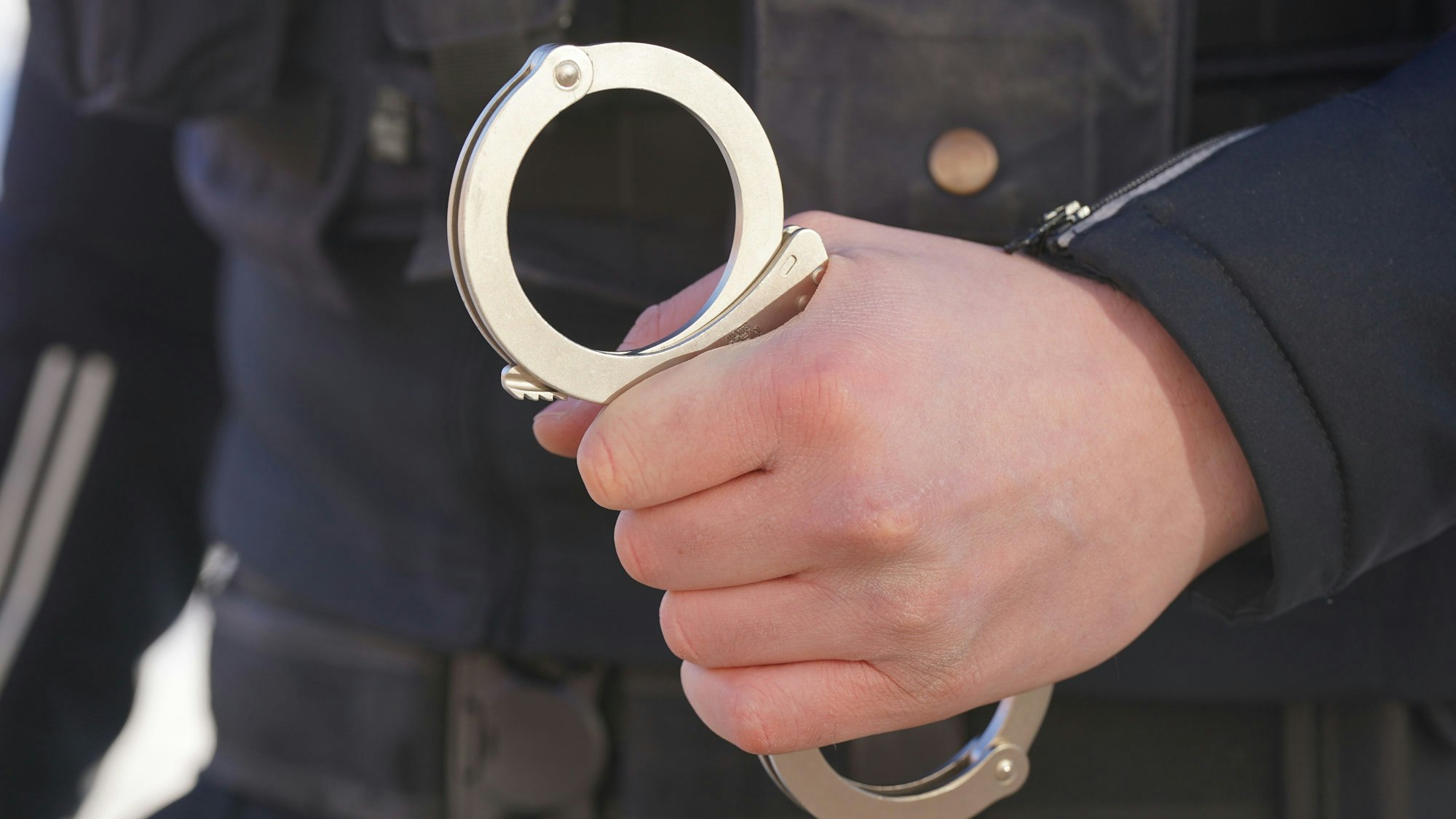 Polizist hält Handschellen in der Hand.