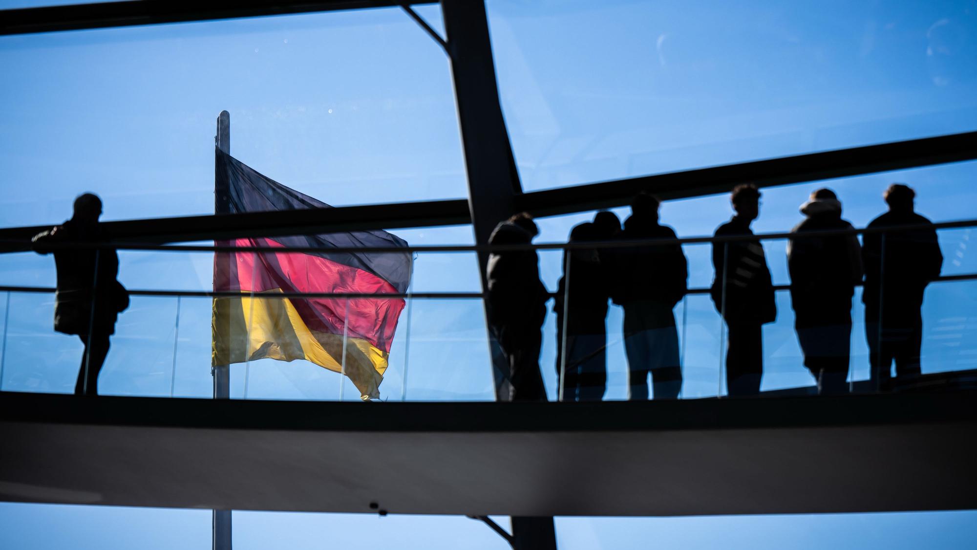 Berlin: Besucher gehen vor der Deutschlandflagge in der Kuppel im Bundestag. Am 23.2.2025 werden die Abgeordneten des Deutschen Bundestags bei vorgezogenen Neuwahlen gewählt.