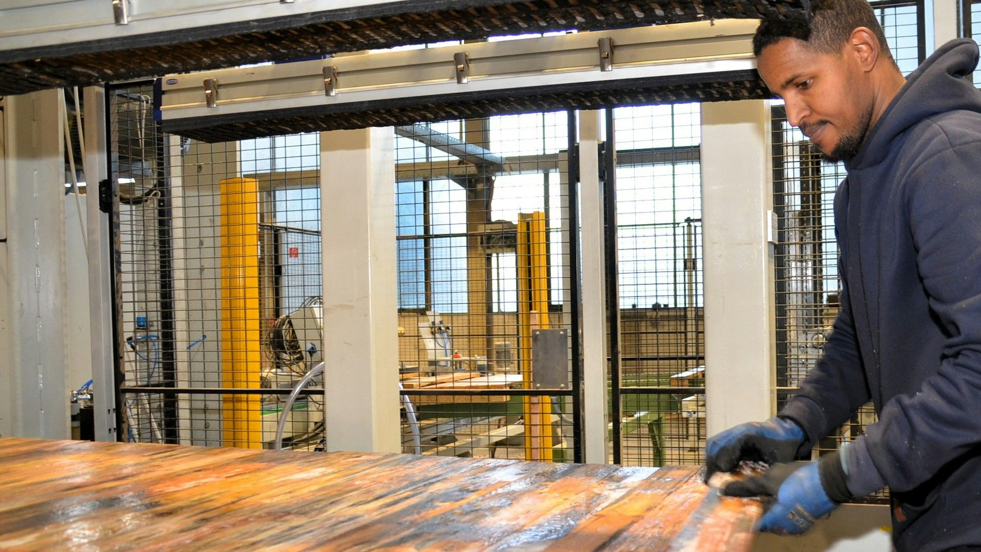 Die Produktion der Holzpaletten beginnt bei Caspari in Waldbröl damit, dass ein Mitarbeiter den Robotor mit frischen Brettern füttert.