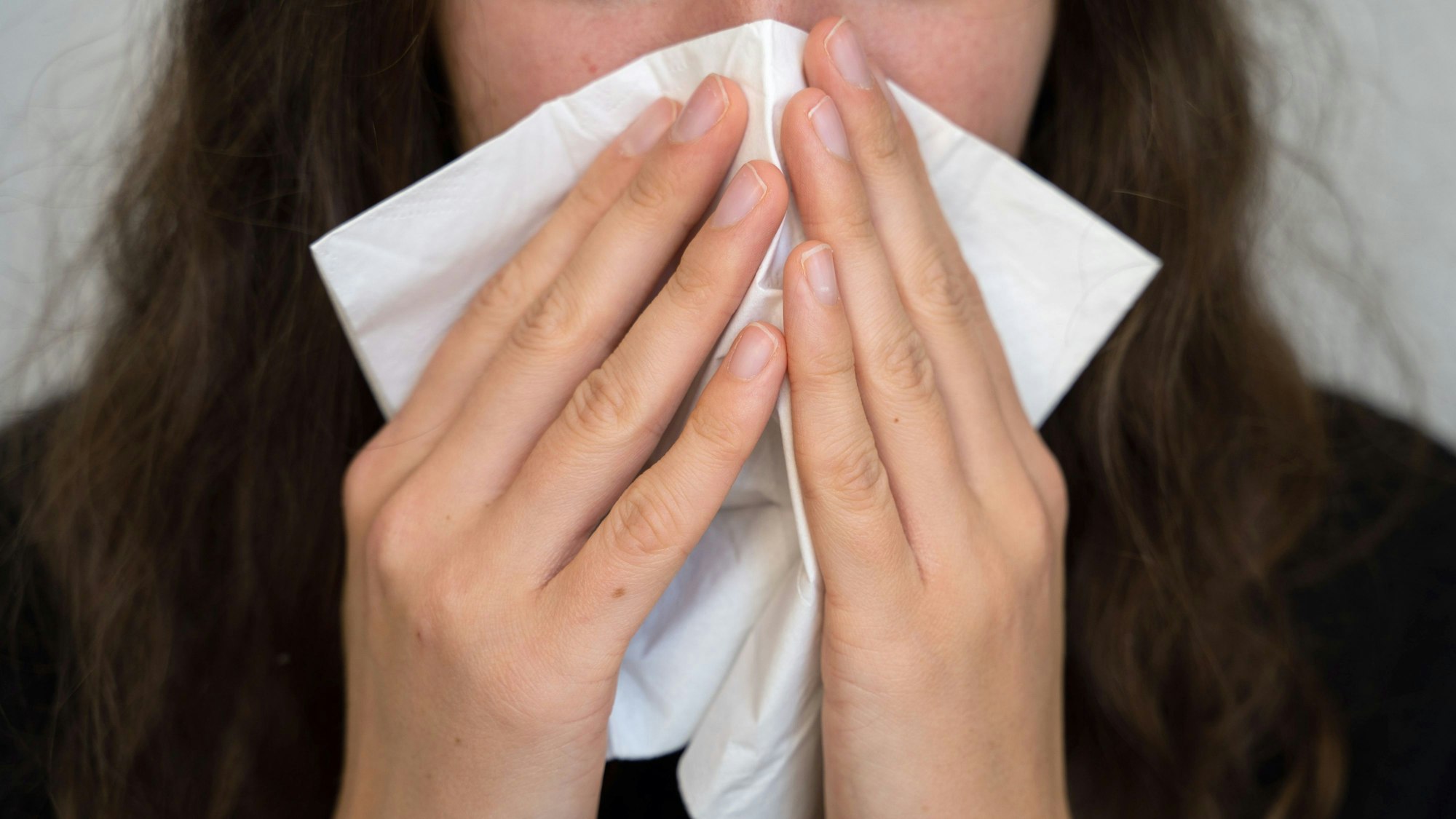 Eine Frau putzt sich die Nase. (Symbolbild)