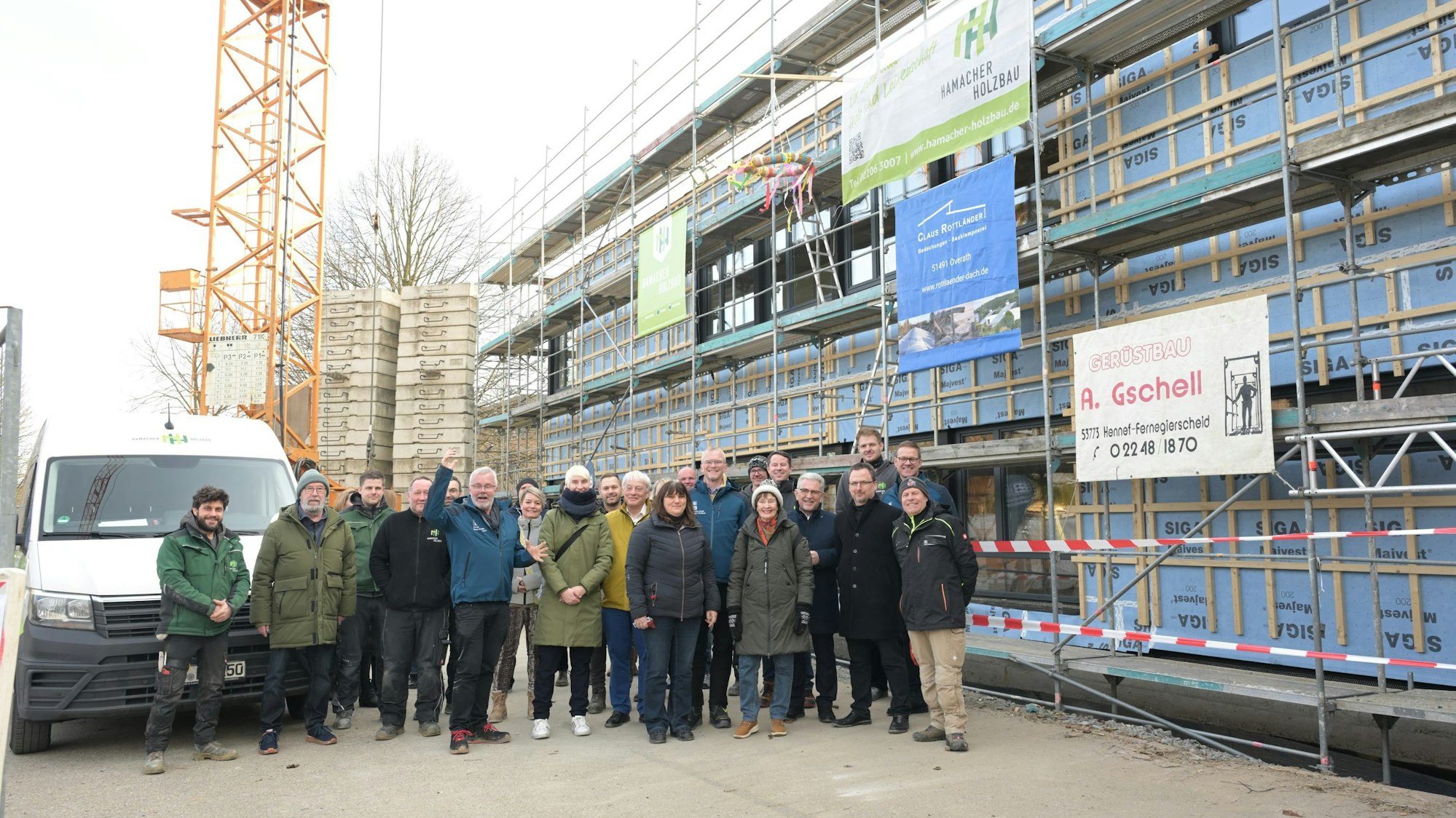 Vor dem eingerüsteten Neubau stehen die eingeladenen Gäste.r