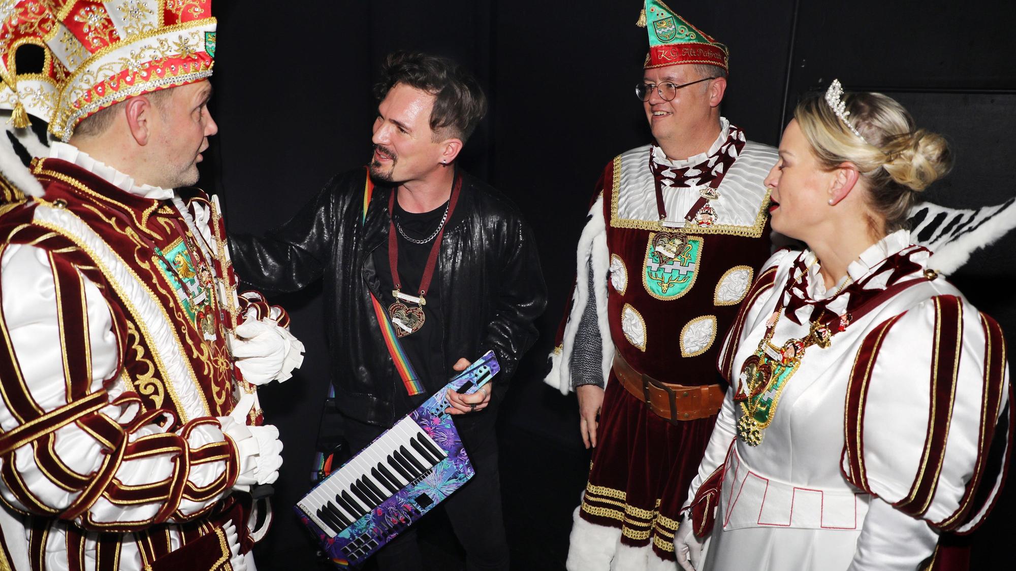 „Cat Ballou“-Keyboarder Dominik Schönenborn begrüßt Prinz Christian I., Bauer Michael und Jungfrau Steffi hinter der Bühne im Bergisch Gladbacher Bürgerhaus Bergischer Löwe.