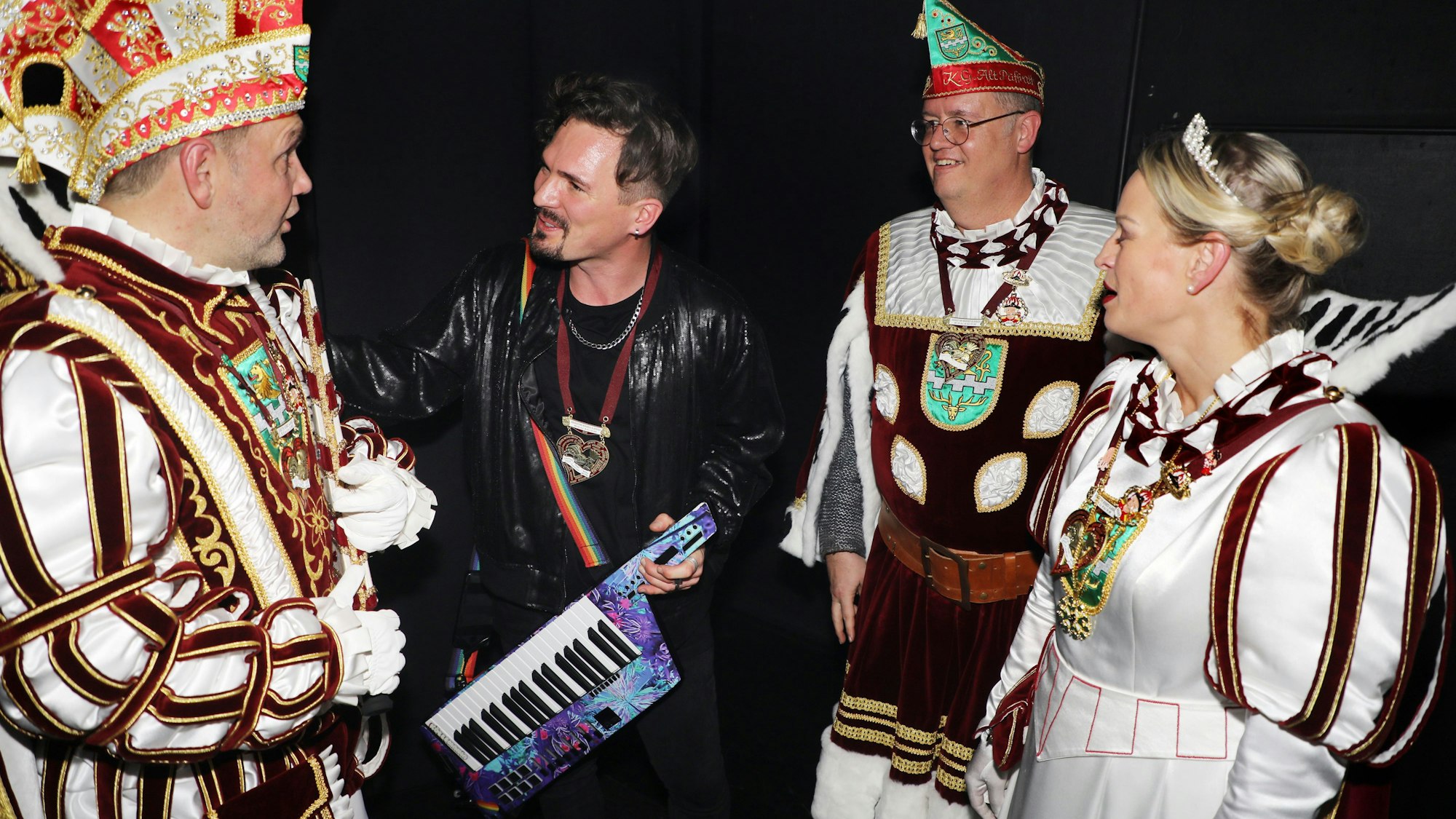 „Cat Ballou“-Keyboarder Dominik Schönenborn begrüßt Prinz Christian I., Bauer Michael und Jungfrau Steffi hinter der Bühne im Bergisch Gladbacher Bürgerhaus Bergischer Löwe.