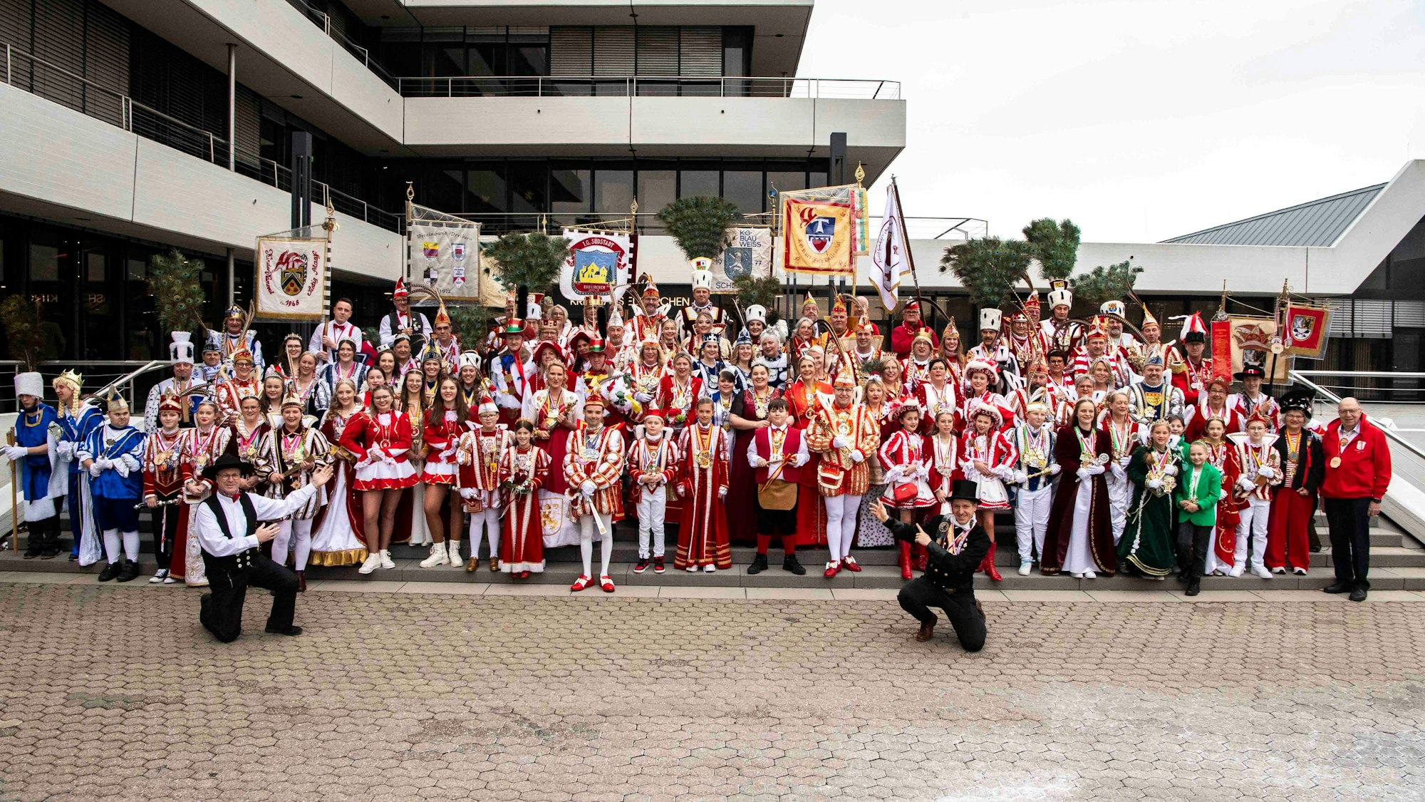 Zahlreiche Karnevalstollitäten stehen auf der Treppe vor dem Kreishaus in Euskirchen. Rechts vor der Gruppe kniet Landrat Markus Ramers in einem Schornsteinfeger-Kostüm.