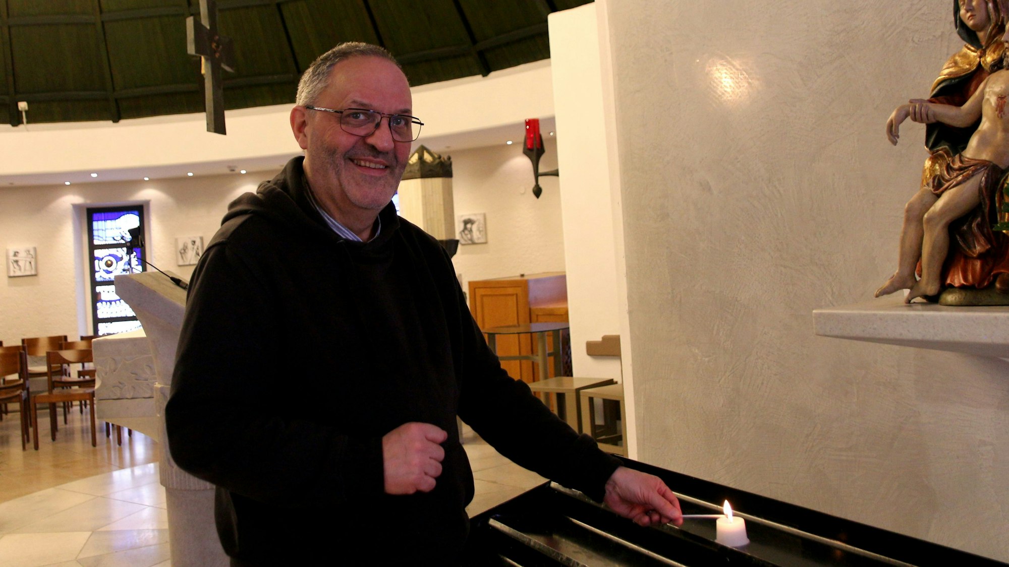 Auf dem Bild ist der Klinikseelsorger in schwarzer Kleidung in der Krankenhauskapelle zu sehen.