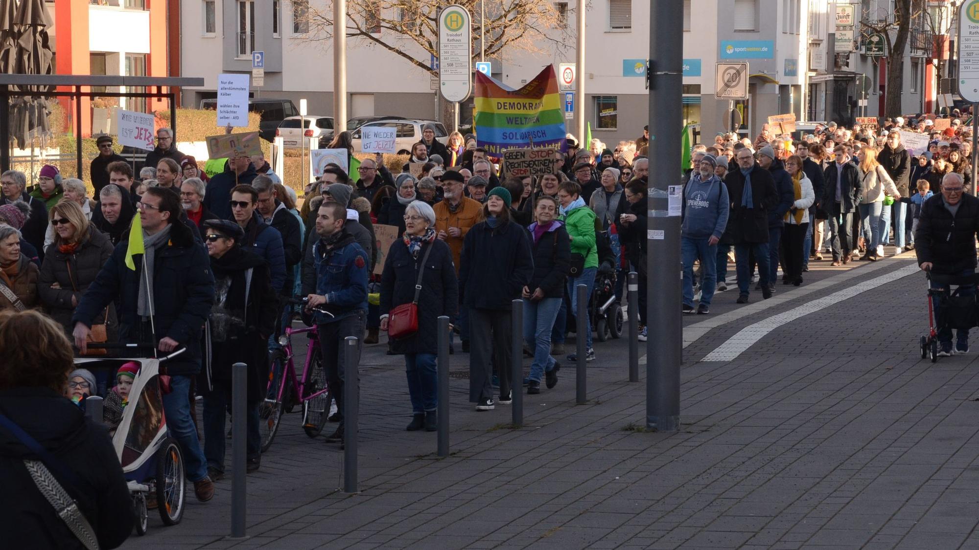 Menschen mit Flaggen und Schildern auf einer Demonstration in Troisdorf.