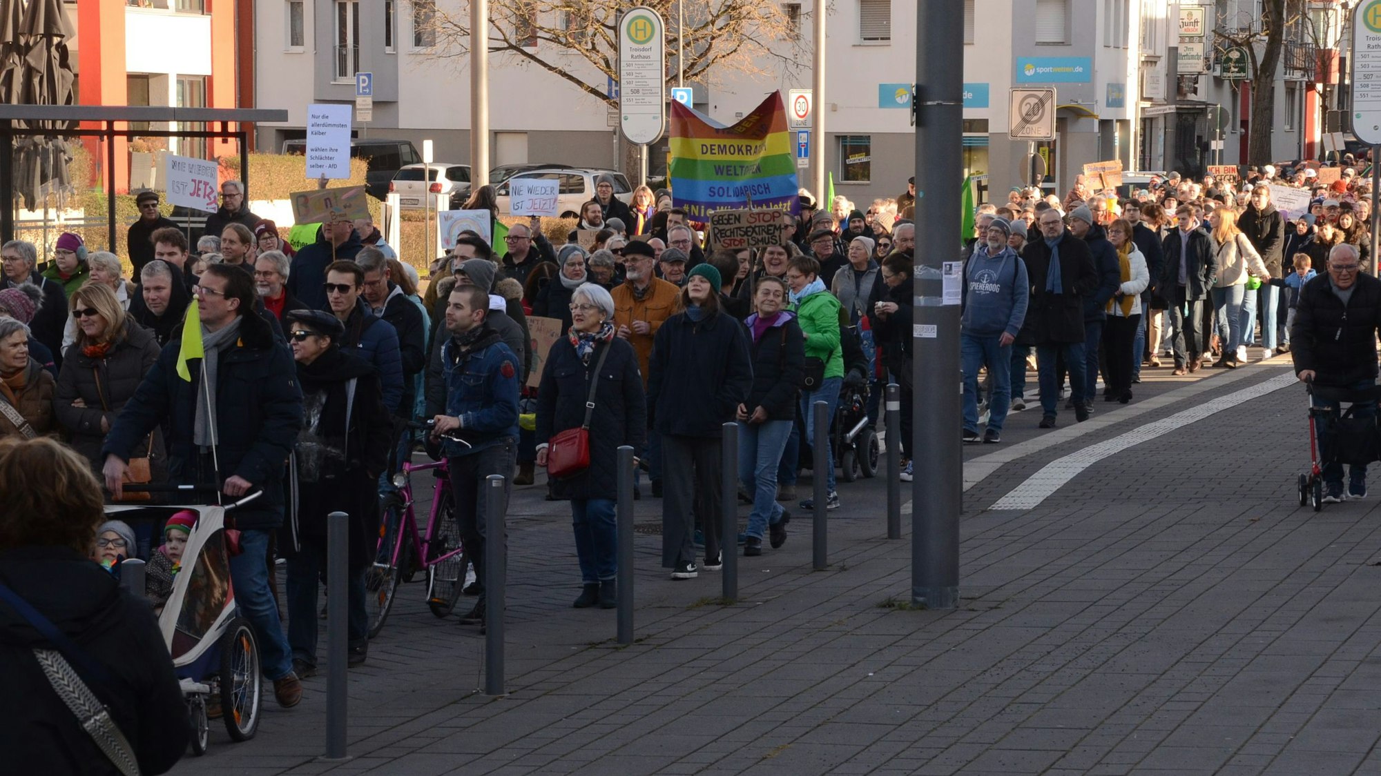 Menschen mit Flaggen und Schildern auf einer Demonstration in Troisdorf.
