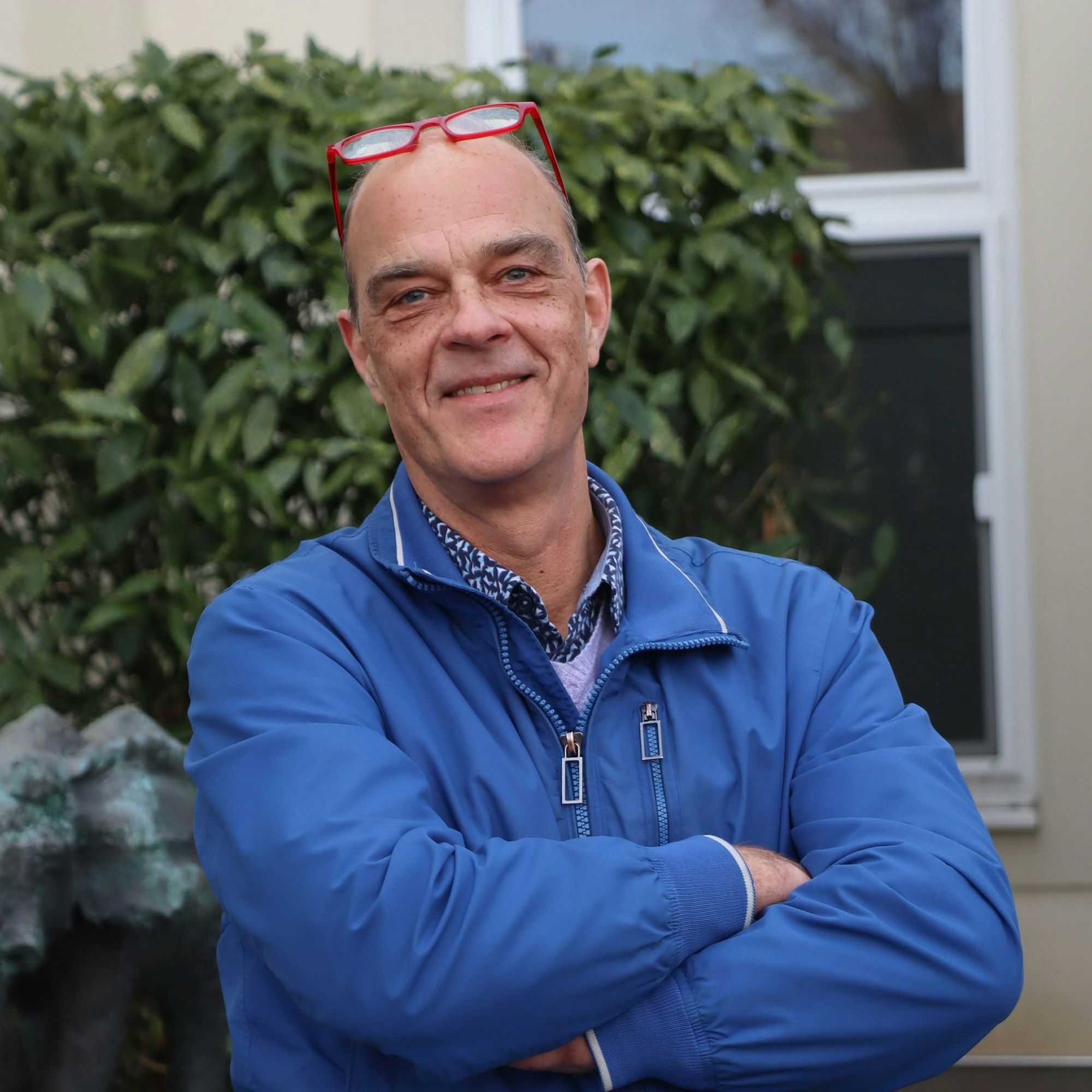 Ein Mann mit überkreuzten Armen lächelt.