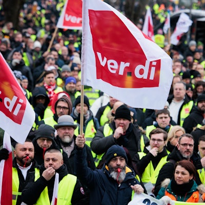 Mitglieder verschiedener Berufsgruppen demonstrieren mit Verdi- Fahnen.