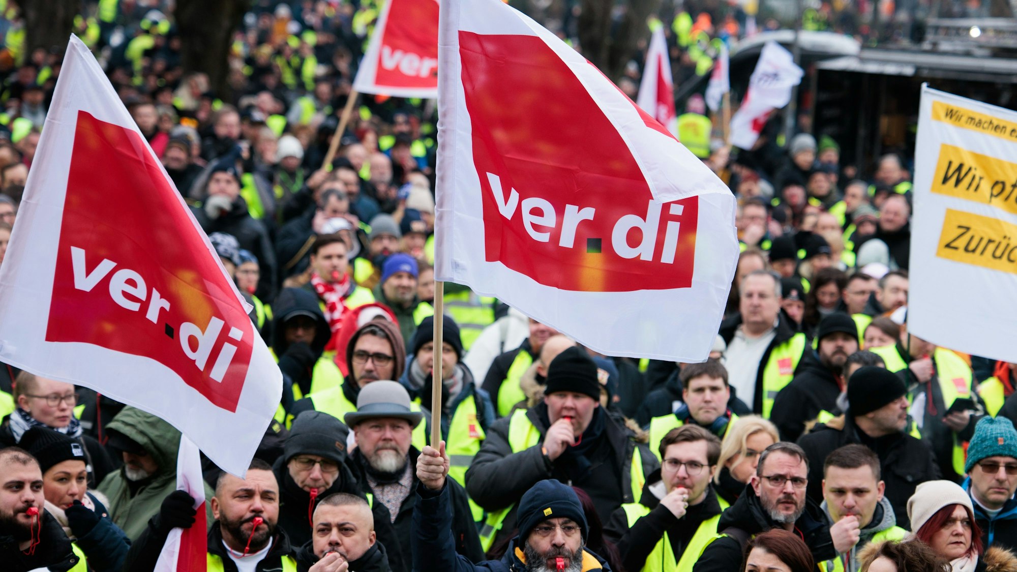 Mitglieder verschiedener Berufsgruppen demonstrieren mit Verdi- Fahnen.
