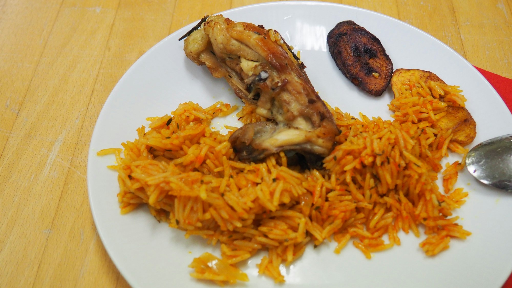 Auf einem Teller sind Reis, Hühnchen und Kochbanane angerichtet.