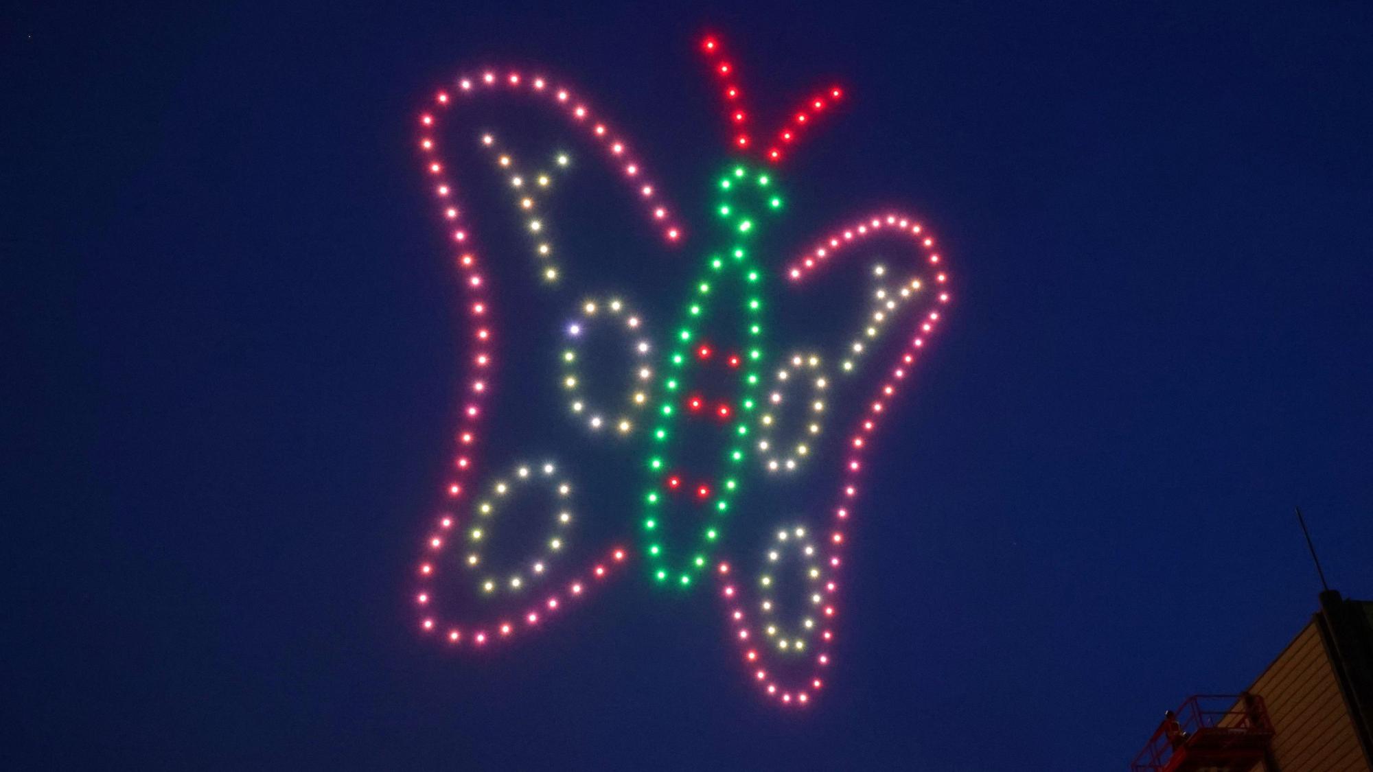 19.02.2025, Nordrhein-Westfalen, Düsseldorf: Über der Messe in Düsseldorf fliegen 200 Drohnen im Form eines bunte Schmetterlings im Rahmen der Industriemesse Xponential. Die Drohnen formten in 90 Metern Höhe unter anderem die Skyline von Düsseldorf, einen Schmetterling sowie eine Weltkugel. Foto: David Young/dpa +++ dpa-Bildfunk +++