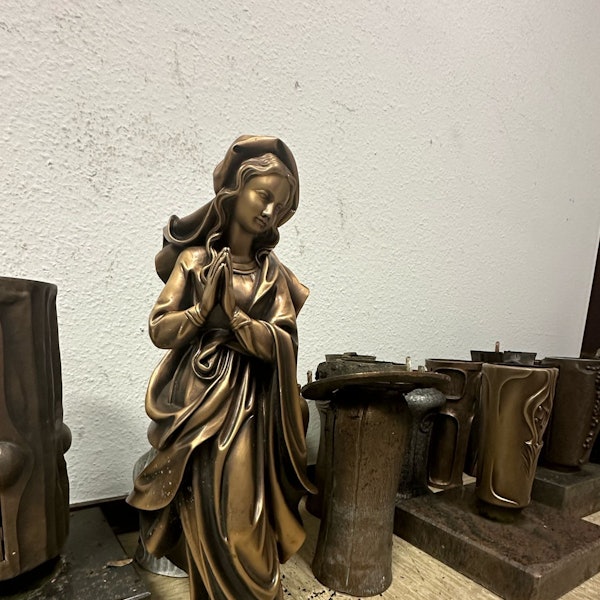 Eine Marienstaue aus Bronze und eine Reihe von Vasen stehen nebeneinander.