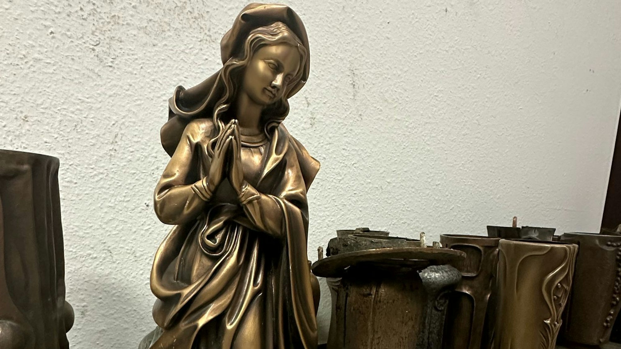 Eine Marienstaue aus Bronze und eine Reihe von Vasen stehen nebeneinander.