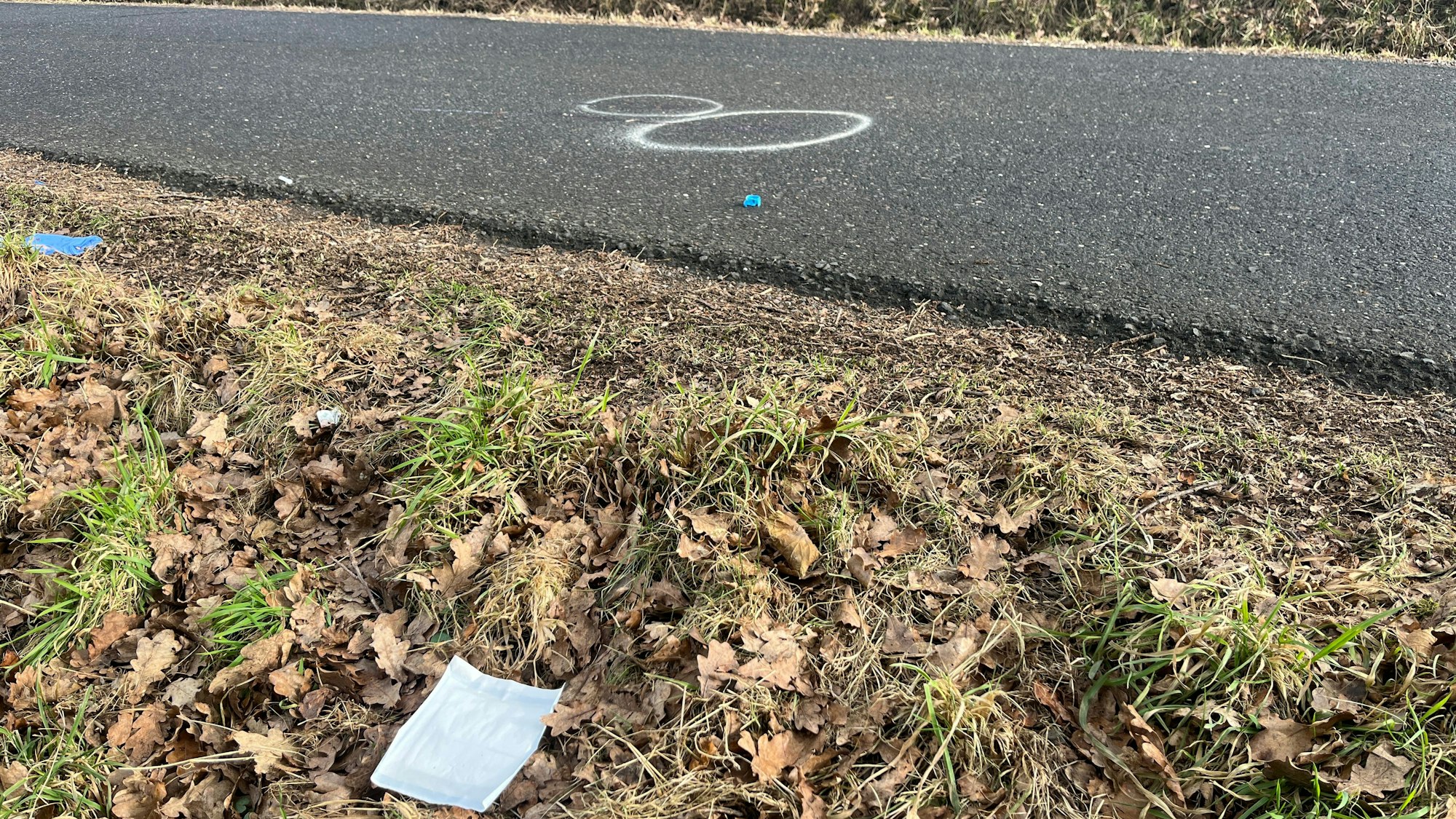 Weiße Kreidekreise sind auf einer schmalen Straße zu sehen.