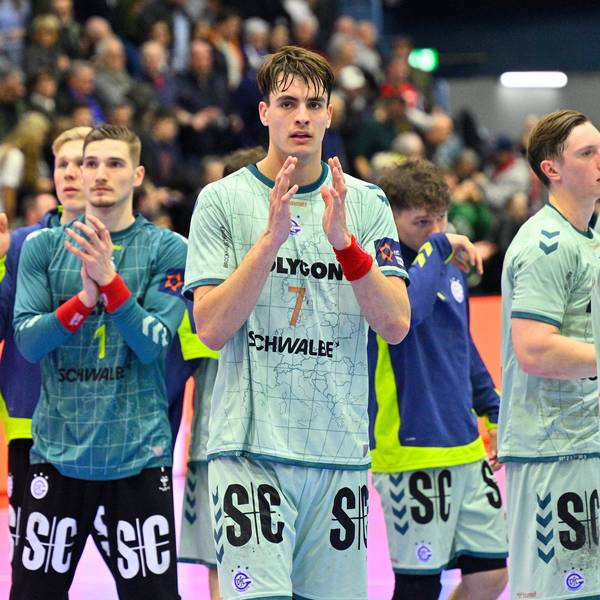 Mehrere Handballer des VfL Gummersbach applaudieren nach einem Spiel gegen Flensburg in Richtung der Fans auf den Tribünen.