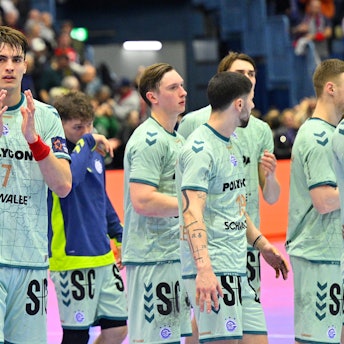 Mehrere Handballer des VfL Gummersbach applaudieren nach einem Spiel gegen Flensburg in Richtung der Fans auf den Tribünen.