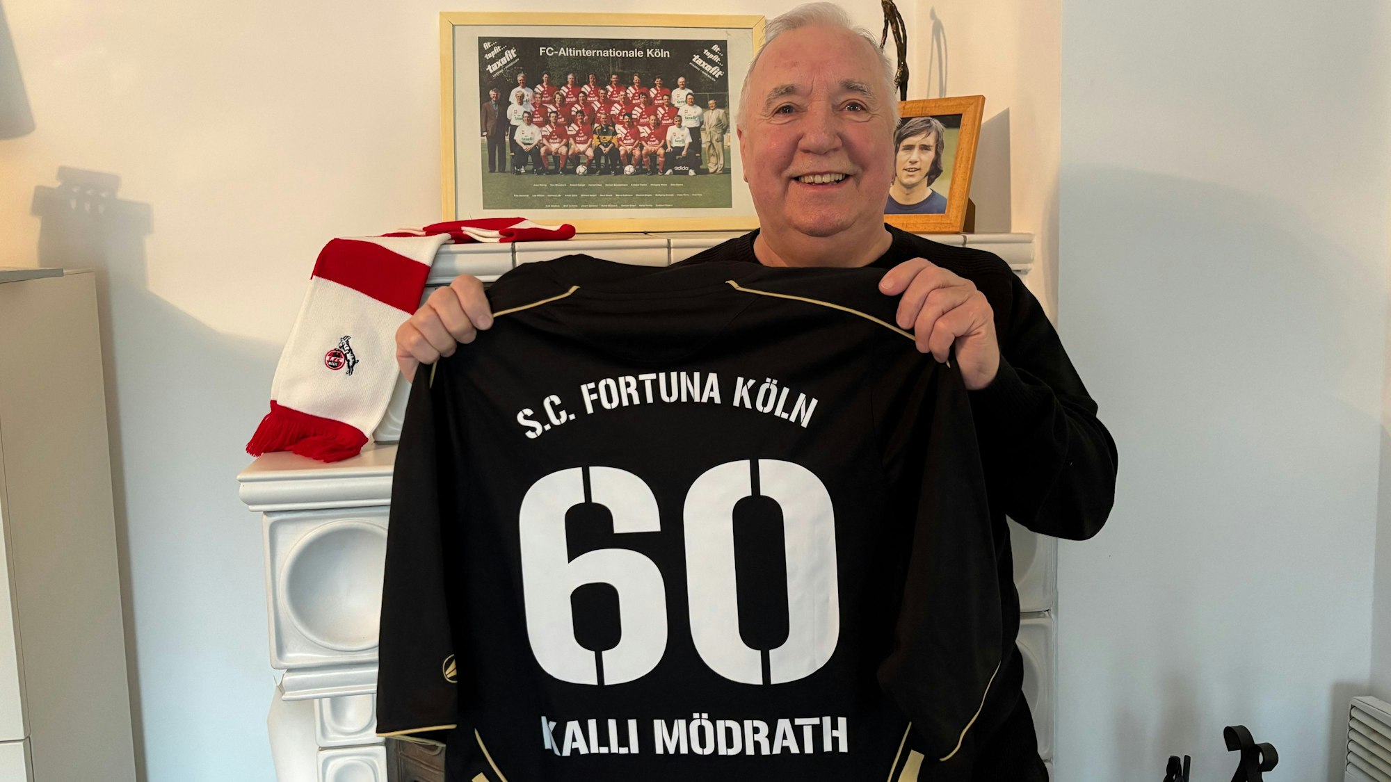 Das Foto zeigt einen Mann, der ein schwarzes Trikot mit der Rückennummer 60 von Fortuna Köln in die Kamera hält