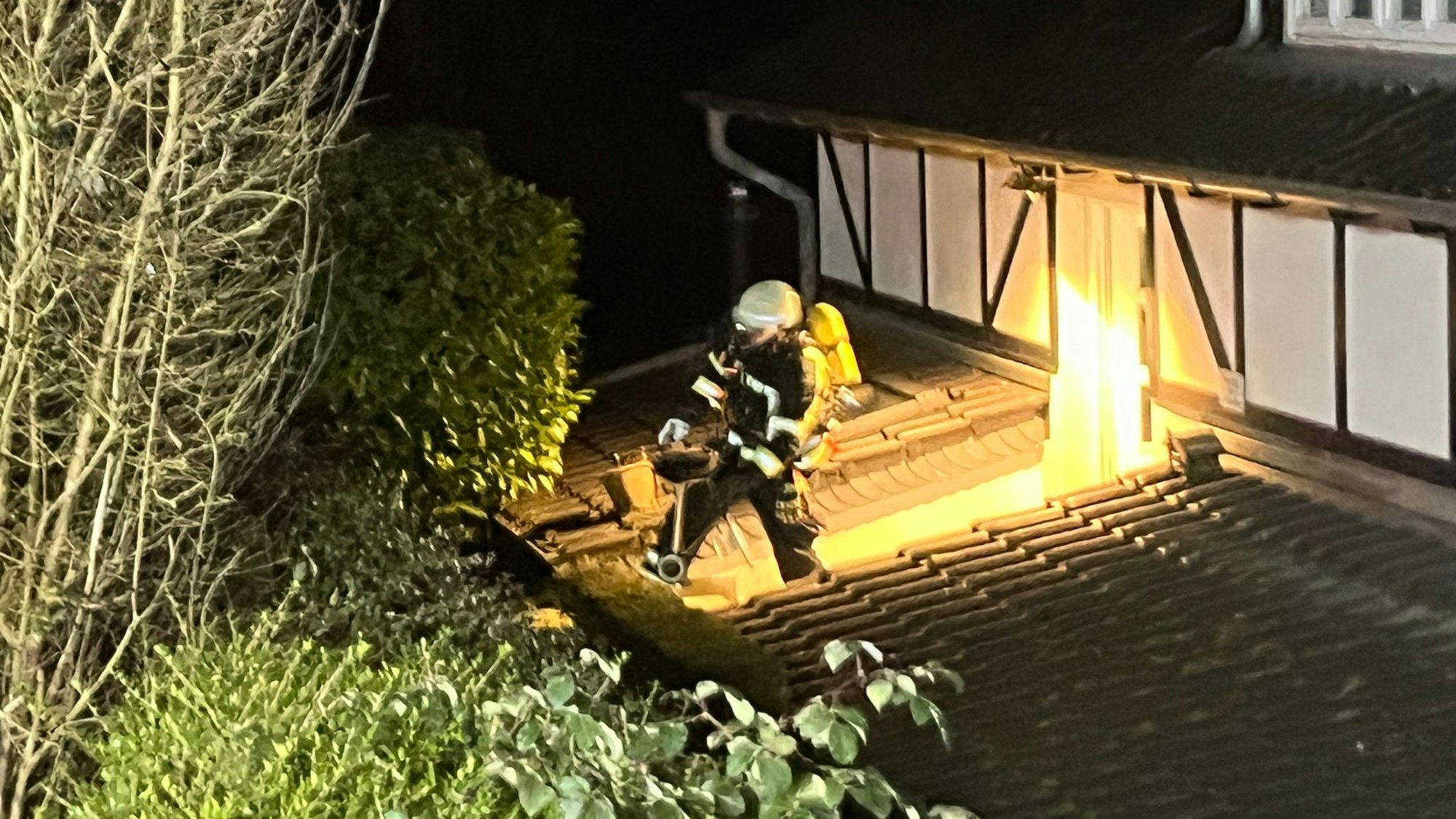 Ein Feuerwehrmann trägt den noch glühenden Grill ins Freie.