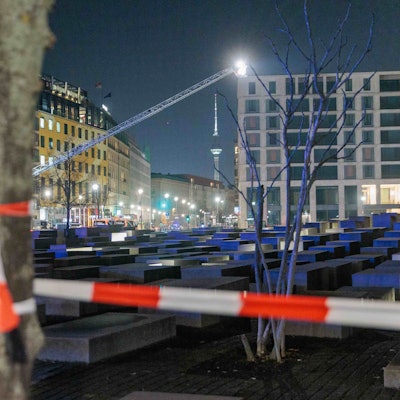 Polizeikräfte und Feuerwehr sichern das Holocaust-Denkmal. Von einer Hebebühne aus durchsuchen sie mit Scheinwerfern das Gelände ab.