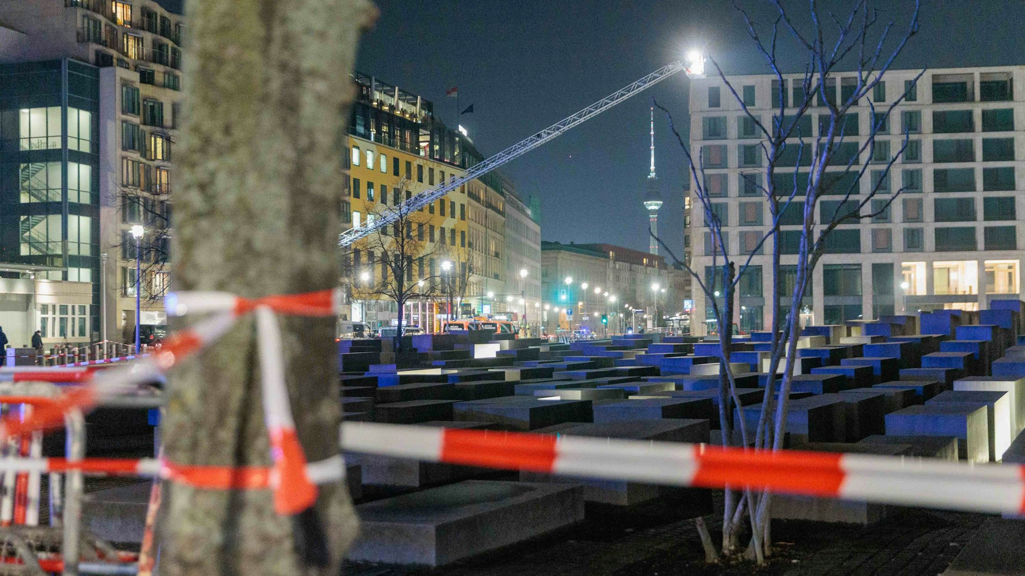 Polizeikräfte und Feuerwehr sichern das Holocaust-Denkmal. Von einer Hebebühne aus durchsuchen sie mit Scheinwerfern das Gelände ab.
