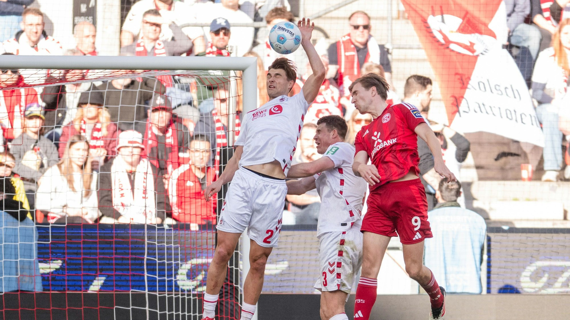 2Blackout: Joel Schmied (l) geht im eigenen Strafraum mit der Hand an den Ball. Daneben Kölns Dominique Heintz (M) und Düsseldorfs Vincent Vermeij.