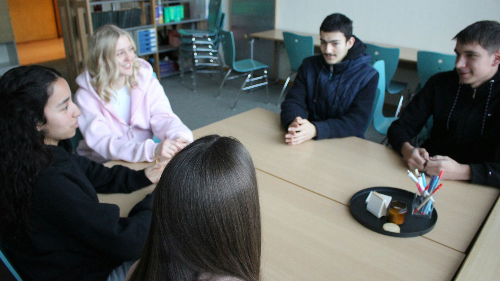 Zu sehen sind Julia, Jana, Mariame, Enes und Kaan, die an einem Tisch sitzen.