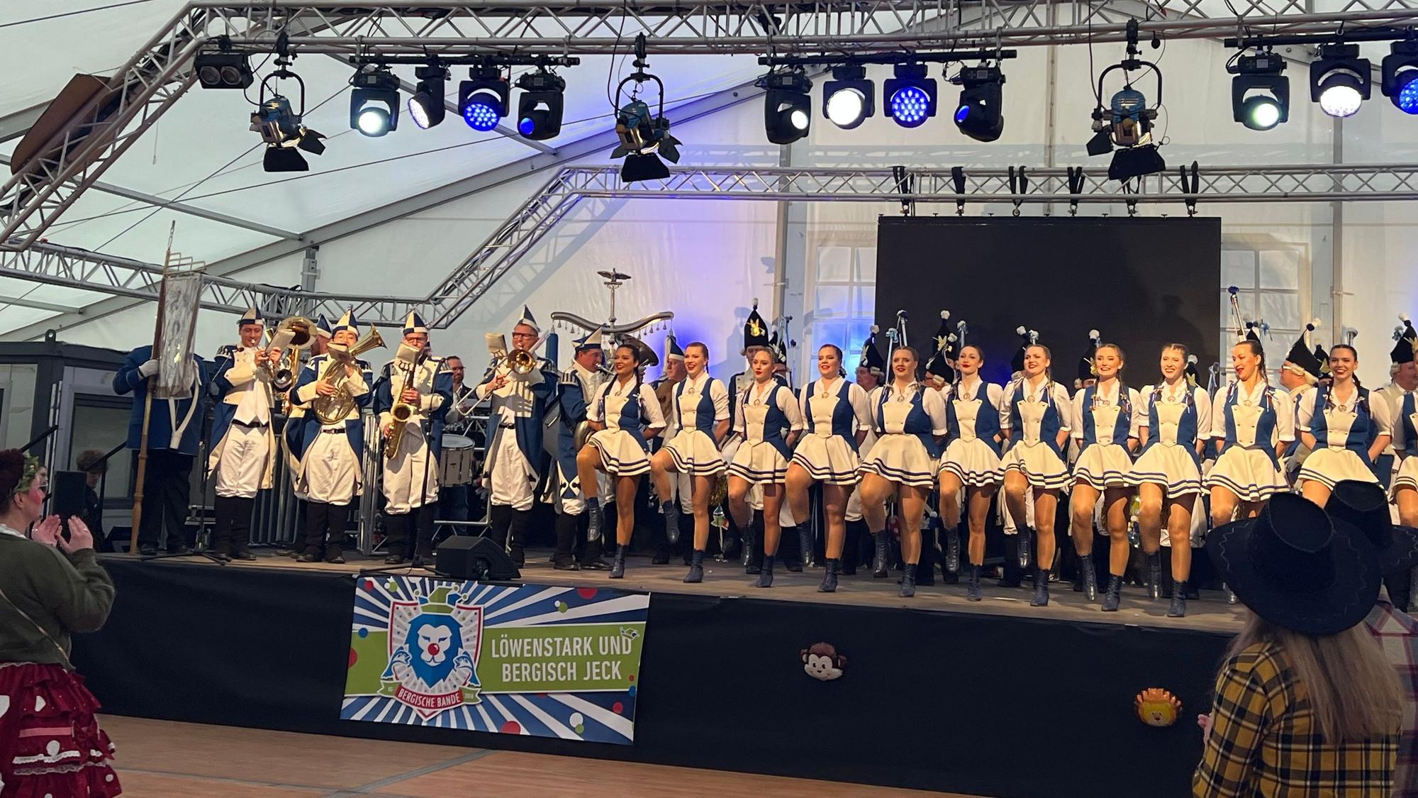 Ein Mädchentanzcorps tanzt auf einer Bühne in einem Festzelt.