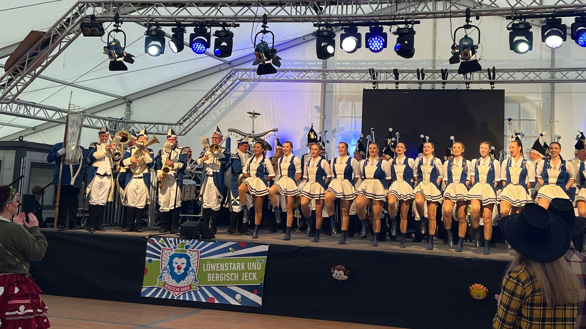 Ein Mädchentanzcorps tanzt auf einer Bühne in einem Festzelt.