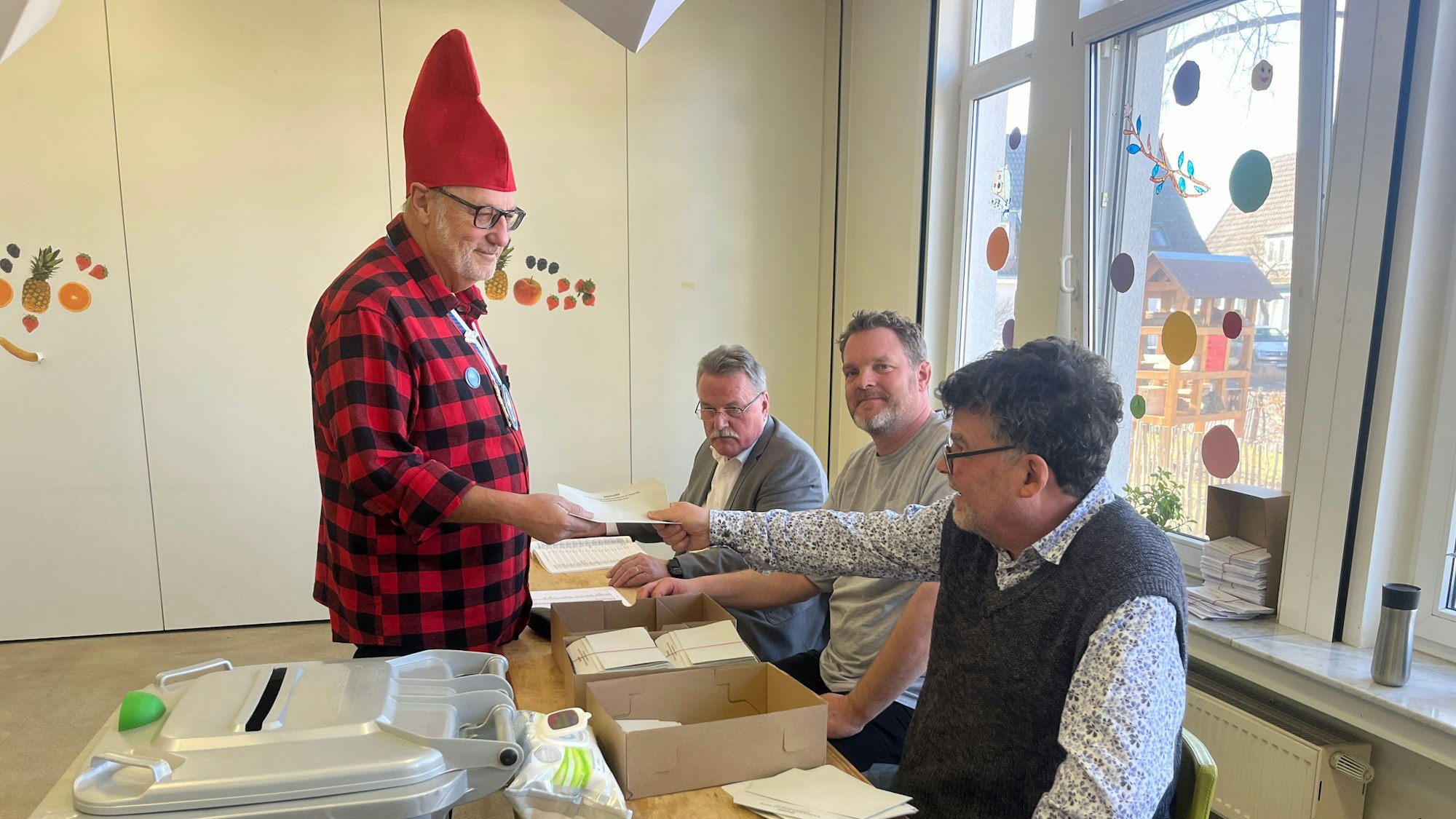 Ein Mann im Kostüm bekommt von einem anderen Wahlzettel gereicht.