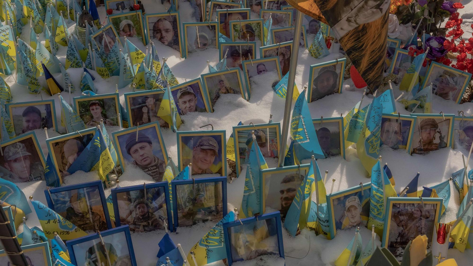 TOPSHOT - This photograph taken on February 23, 2025, shows portraits of soldiers in snow at the makeshift memorial paying tribute to Ukrainian and foreign fighters at the Independence Square in Kyiv, on February 23, 2025, ahead of the third anniversary of Russia's invasion of Ukraine. (Photo by Roman PILIPEY / AFP)